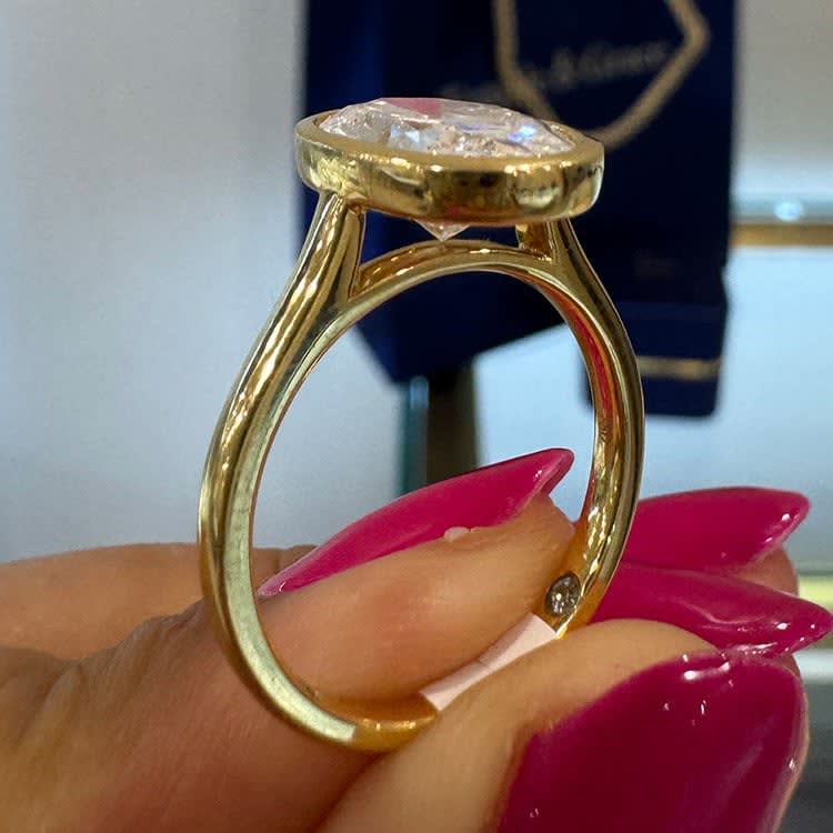 Oval diamond set in bezel setting in yellow gold