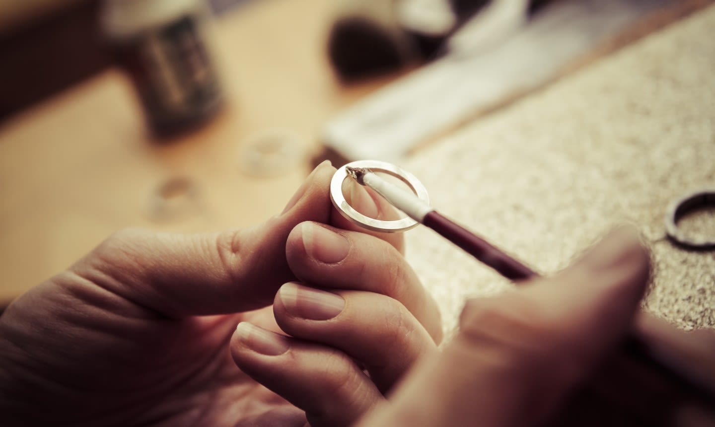 Couple learning from experienced jeweller they make their own wedding rings
